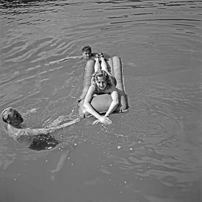 Impression encadrée : Freizeit. Une femme sur une matrasse en airs et deux hommes nageant autour