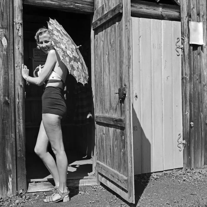 Framed Print : Freizeit. Eine junge Frau im Badeanzug mit Sonnenschirm am Eingang zu einer Holzhütte Framed Print : Freizeit. Eine junge Frau im Badeanzug mit Sonnenschirm am Eingang zu einer Holzhütte
