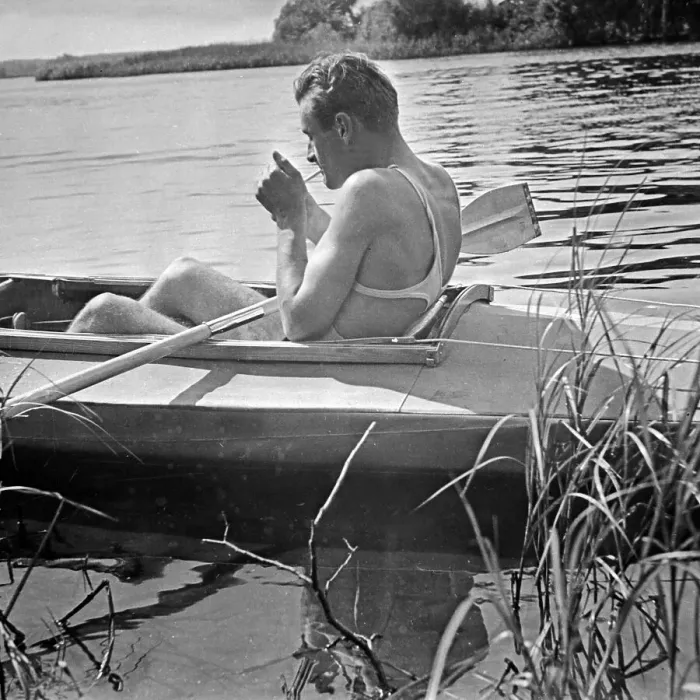 Impression encadrée : Freizeit. Un homme allume une cigarette dans son bateau pliable klepp en