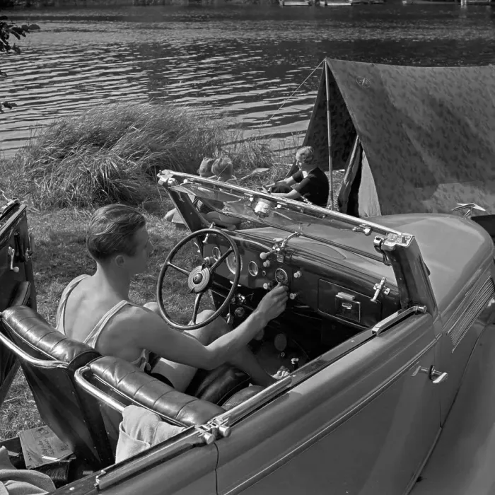 Stampa con cornice : Freizeit. Un uomo alla guida del suo Ford V8 cabrio davanti ad un tenda Stampa con cornice : Freizeit. Un uomo alla guida del suo Ford V8 cabrio davanti ad un tenda