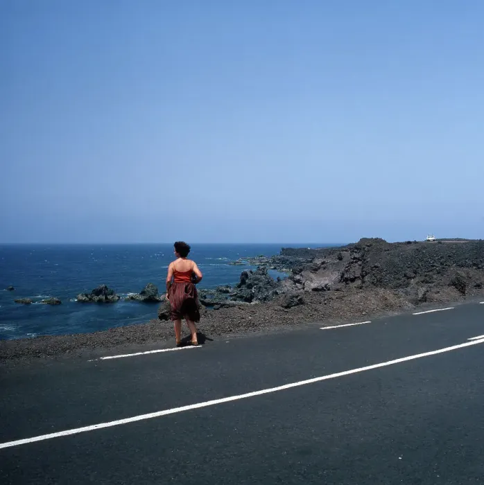 Framed Print : Lanzarote. Eine Frau steht auf einer Straße bei Los Hervideros an der Westküste Framed Print : Lanzarote. Eine Frau steht auf einer Straße bei Los Hervideros an der Westküste
