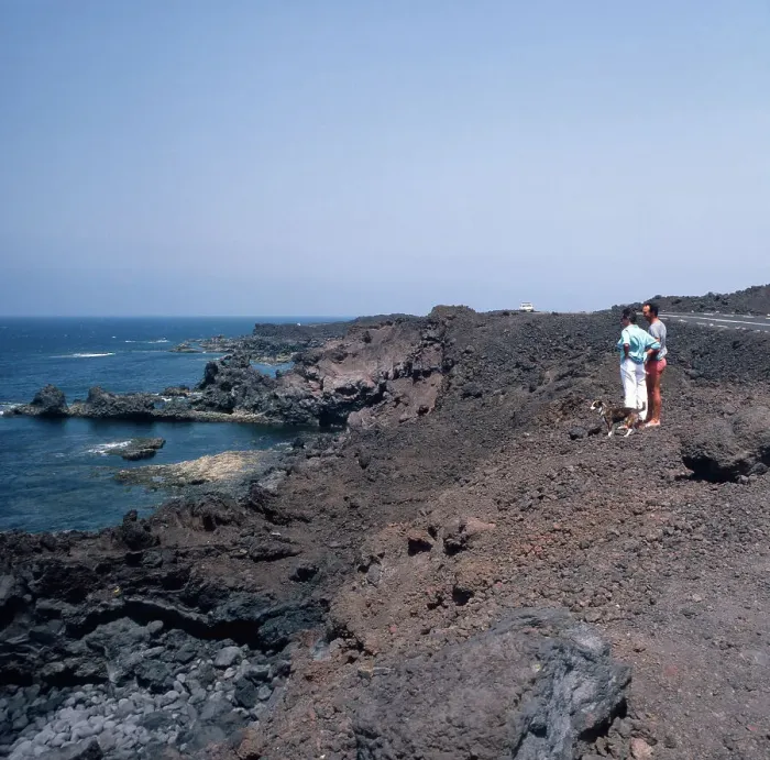 Stampa con cornice : Lanzarote. Un coppia in una strada vicino a Los Hervideros sulla costa