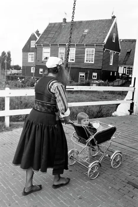 Impression encadrée : Marken. La mère jeune pousse son chariot à enfant dans les rues du village Impression encadrée : Marken. La mère jeune pousse son chariot à enfant dans les rues du village