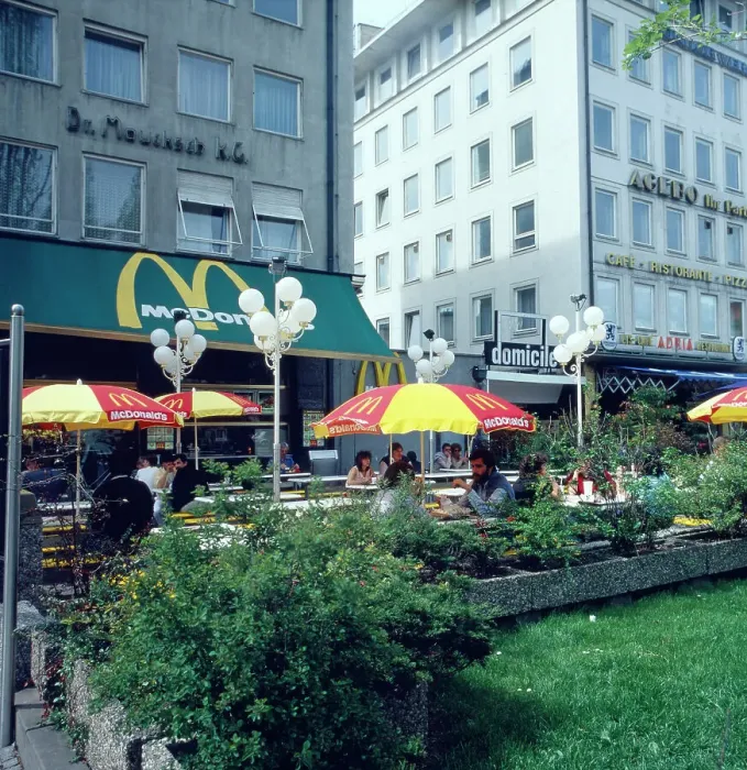 Stampa con cornice : München. Munich, 1985. Caffè stradale all'incrocio di Via Leopold a Schwaningen Stampa con cornice : München. Munich, 1985. Caffè stradale all'incrocio di Via Leopold a Schwaningen