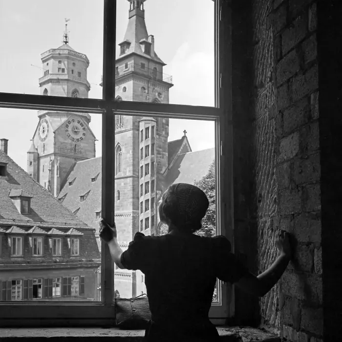 Gerahmter Druck : Stuttgart. Eine Frau schaut aus einem Fenster heraus auf die Stiftskirche