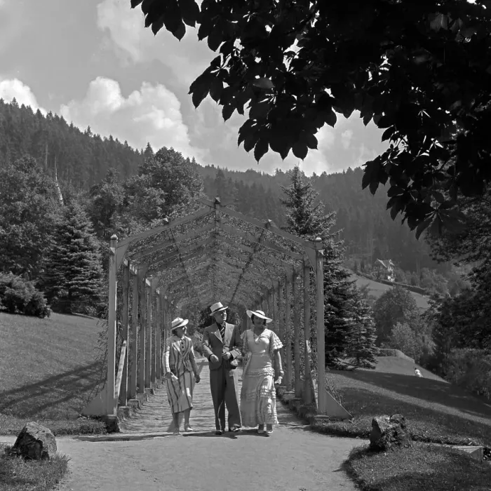 Gerahmter Druck : Wildbad. Ein Mann geht mit zwei Frauen durch das Rankgerüst am Schlossparkplatz