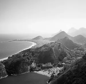 Drucke von Die Küste von Rio de Janeiro, Brasilien - ein Bild der Eleganz und Schönheit. Die Wellen schlagen sanft gegen die Felsen, während im Hintergrund die majestätischen Berge aufragen Hanna Seidel Drucke: Brasilienküste bei Rio de Janeiro, Brasilien 1966